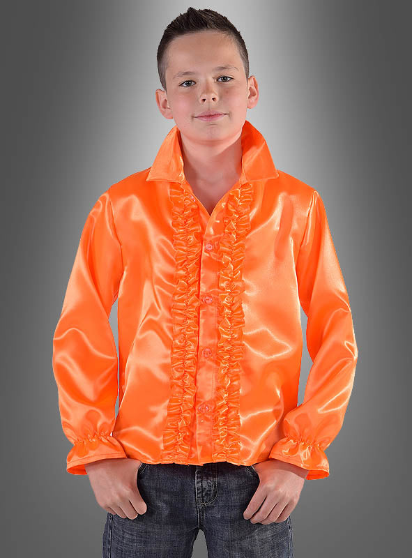 Ein junger Mensch trägt ein leuchtend orangefarbenes Rüschenhemd für Kinder in verschiedenen Farben, kombiniert mit Jeans, und steht vor einem grauen Hintergrund mit Farbverlauf – das ideale 70er-Jahre-Kostüm oder Disco-Party-Outfit für jede Feier im Retro-Stil.
