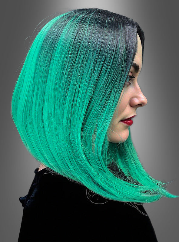 Frau im Profil mit glattem, schulterlangem Haar in leuchtendem Grün mit schwarzen Ansätzen, die ein schwarzes Oberteil trägt, vor einem schlichten grauen Hintergrund. Dieser auffällige Look besticht durch die „Zwei-Ton-Farbe-Perücke Lilia“, die mit einem trendigen zweifarbigen Farbverlauf gestylt ist.