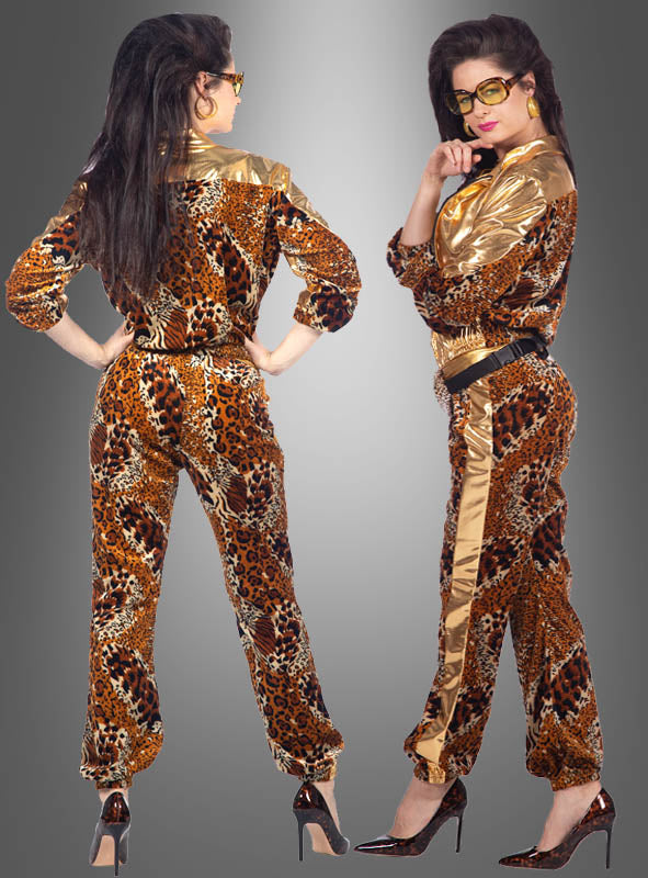 Zwei Frauen posieren in „80er Trainingsanzug Glamping Panther“-Jumpsuits mit schwarzen Gürteln und High Heels vor einem grauen Hintergrund mit Farbverlauf – die perfekte Kleidung für jede 80er-Jahre-Mottoparty.