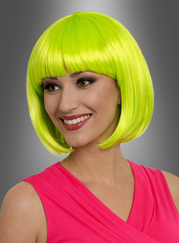 Eine lächelnde Frau trägt die „Farbenfrohe Foxy Neon Bobfrisur“ in leuchtendem Neongrün, kombiniert mit einem ärmellosen rosa Oberteil für einen authentischen 80er-Jahre-Kostüm-Look, und posiert vor einem grauen Hintergrund mit Farbverlauf.