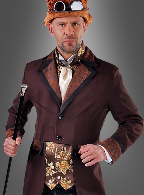 Ein Mann im „Steampunk Gentleman“-Kostüm – bestehend aus einem braunen Anzug mit Zylinder, Schutzbrille, verzierter Weste und Krawatte – steht vor einem grauen Hintergrund und hält einen schwarzen Spazierstock in der Hand. Er verkörpert damit klassische viktorianische Herrenmode, die mit unverwechselbarem Steampunk-Flair angereichert ist.