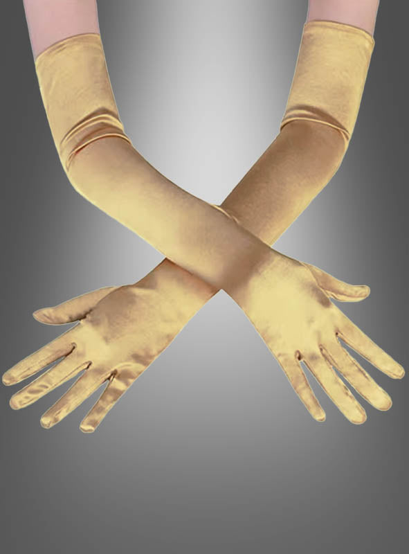 Zwei Arme, die lange, glänzende goldene Satinhandschuhe in verschiedenen Farben tragen, sind an den Handgelenken vor einem grauen Hintergrund mit Farbverlauf gekreuzt.