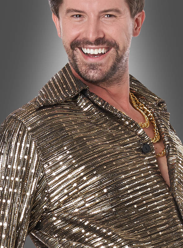Ein lächelnder Mann im „Disco Fever“-Herrenkostüm in Gold und Schwarz, bestehend aus einem glänzenden, goldfarbenen Paillettenhemd und einer goldenen Kette, verkörpert vor einem grauen Hintergrund perfekt den klassischen Kostümstil der 70er Jahre.