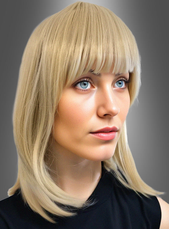 Eine Person mit glattem, schulterlangem blondem Haar und Pony trägt ein schwarzes Oberteil und posiert vor einem grauen Hintergrund mit Farbverlauf. Der Look besticht durch die schulterlange Perücke „Julia Deluxe“, die mühelosen Chic und moderne Raffinesse ausstrahlt.