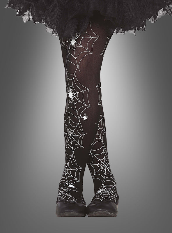 Spinnennetz-Strumpfhose für Kinder in Schwarz mit weißen Spinnennetz- und Spinnenmotiven, ideal als Halloween-Strumpfhose, kombiniert mit schwarzen Schuhen und einem schwarzen Rüschenrock vor einem grauen Farbverlaufshintergrund.