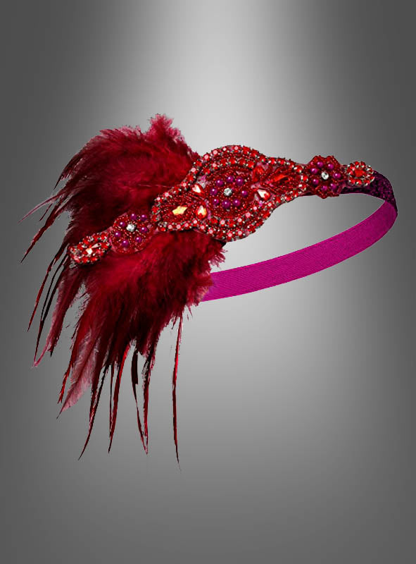 Ein Haarband im Stil der 20er Jahre mit Strass und Perlen namens „Lilli“, das auf einer Seite mit roten Federn verziert ist und von glamourösen Flapper-Kleid-Outfits inspiriert wurde, vor einem Farbverlauf aus Grautönen.