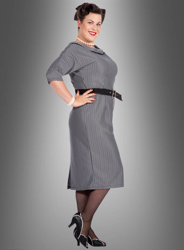 Eine Frau steht im Profil vor einem grau verlaufenden Hintergrund, lächelt mit den Händen in den Hüften und trägt das Bleistiftkleid „Jackie Rockabilly“ im Stil der 50er Jahre, kombiniert mit einem schwarzen Gürtel, Strümpfen und Pumps.