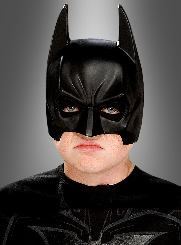Eine Person, die die „Batman-Maske für Erwachsene“ und ein schwarzes Kostüm trägt, blickt vorwärts vor einem grauen Hintergrund mit Farbverlauf.