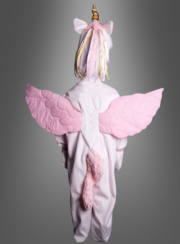 Ein Kind, das das „Zauberhaftes Plüsch-Einhorn-Kostüm Deluxe“ trägt – mit rosa Flügeln, einem Schwanz und einem goldenen Horn –, steht mit dem Rücken zu einem grauen Hintergrund – damit ist es die perfekte Wahl unter den Tierkostümen für Mädchen zu Fasching, Karneval oder Halloween.