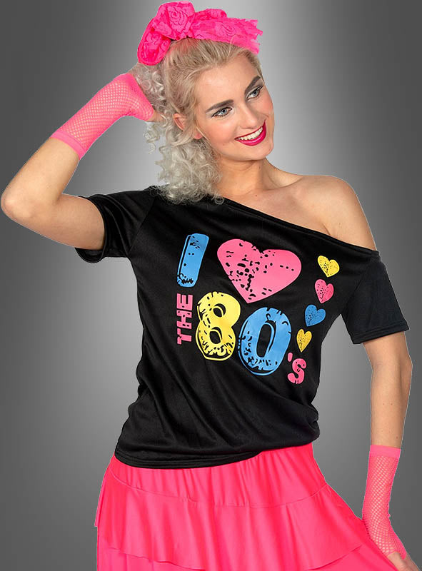 Eine Frau mit blonden Haaren, einem rosa Stirnband und Handschuhen trägt das schwarze 80er-Shirt „Cold Shoulder Damen“ mit dem dem Aufdruck „I love the 80s“ und einen rosa Rock und verkörpert damit perfekt die ikonische 80er-Jahre-Mode, während sie mit einem Arm hinter dem Kopf vor einem grauen Hintergrund posiert – die ideale Inspiration für deine nächste 80er-Mottoparty.