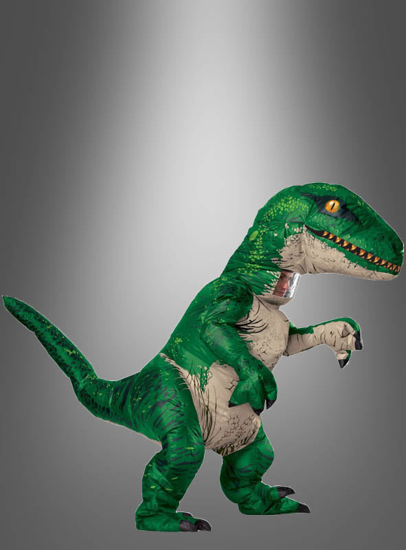 Eine Person, die das „Jurassic World Velociraptor Dino-Kostüm mit Sound“ trägt – ein beeindruckendes aufblasbares Kostüm –, steht aufrecht vor einem grauen Hintergrund mit Farbverlauf.
