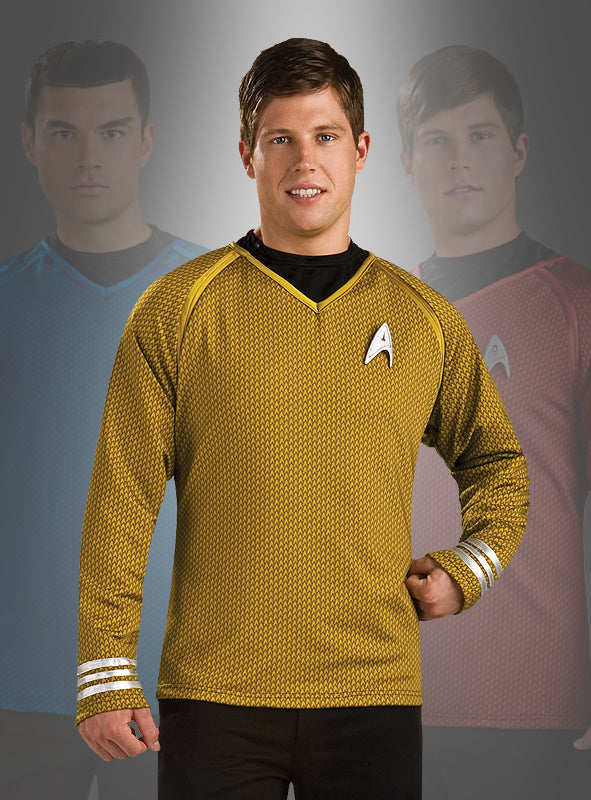Drei Männer in „Star Trek“-Uniformen – einer in Blau, einer in Rot und einer, der das goldene „Star Trek XI Grand Heritage“-Shirt mit dem Kirk-Aufdruck trägt – stehen nebeneinander, wobei der Mann im goldenen Kirk-Shirt ganz vorne steht und in die Kamera lächelt.