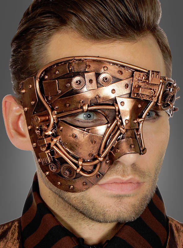 Ein Mann, der eine Steampunk-Halbmaske im Stil der 20er Jahre in Metallic-Kupfer oder -Gold trägt, die mit Zahnrädern und Nieten verziert ist und die rechte Seite seines Gesichts bedeckt.