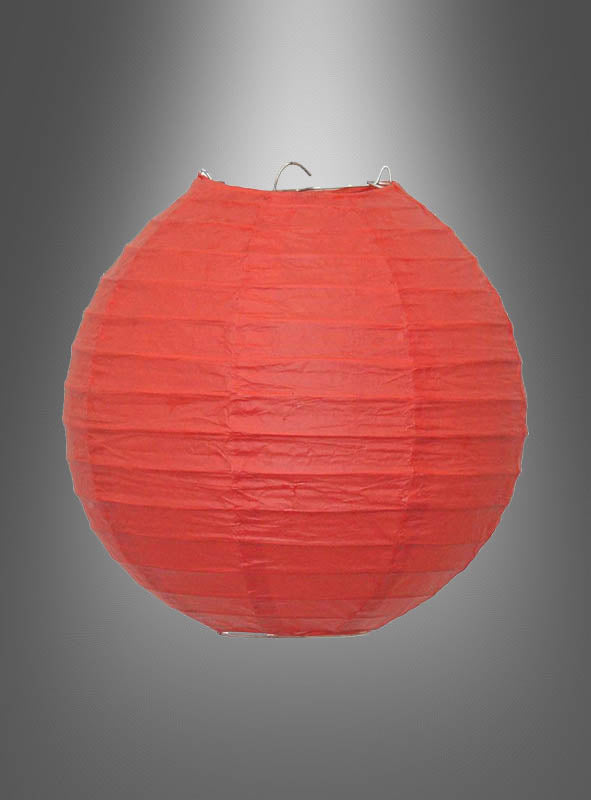Ein runder roter „Papierlampion in kräftigen Farben (20–45 cm)“ mit einem stabilen Metallrahmen ist vor einem grauen Hintergrund mit Farbverlauf aufgehängt und eignet sich somit ideal als Partydekoration für Ihre nächste Gartenparty.