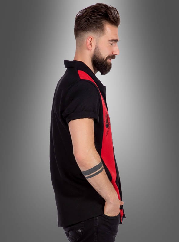 Ein bärtiger Mann steht im Profil da und trägt das klassische schwarz-rote „Rockabilly Hemd Dean“ mit hochgekrempelten Ärmeln, eine dunkle Hose und ein auffälliges Armband-Tattoo auf dem Unterarm.