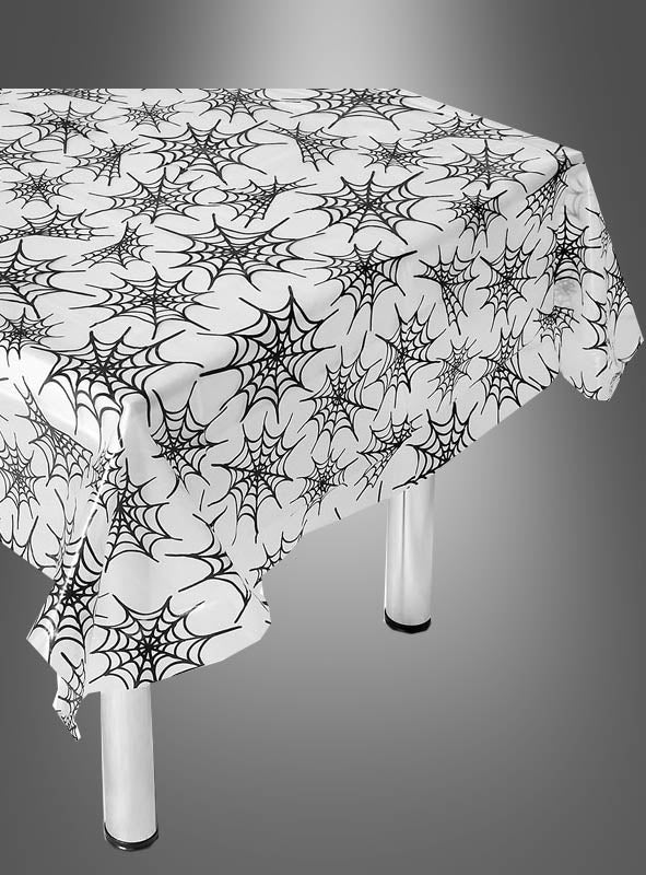 Ein rechteckiger Tisch, gedeckt mit der „Halloween Mehrweg-Tischdecke Spinnen & Netze“ – einer weißen, wiederverwendbaren Tischdecke mit schwarzem Spinnennetzmuster auf einfarbigem grauen Hintergrund – eine perfekte Ergänzung für Ihre Halloween-Dekoration.