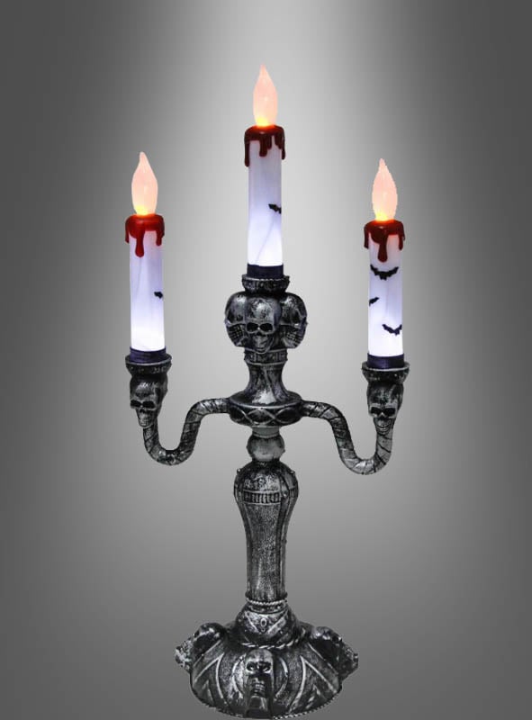 Der Kerzenleuchter mit LED-Lichtern verfügt über drei gotische Arme, die mit Totenkopf- und Fledermausmotiven verziert sind. An jedem Arm befindet sich eine weiße Kerze mit roten Wachstropfen und flackernden, flammenförmigen LED-Glühbirnen, was ihn zur perfekten Halloween-Dekoration macht.