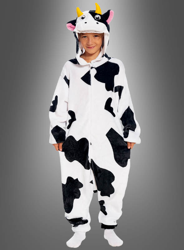 Ein Kind, das den „Kuh-Overall für Kinder“ trägt – einen schwarz-weißen Overall mit Kuhmuster, Kapuze, Kuhöhrchen und gelben Hörnern, der sich perfekt als Kuscheloverall oder Kuhkostüm für Kinder eignet –, steht vor einem grauen Hintergrund.