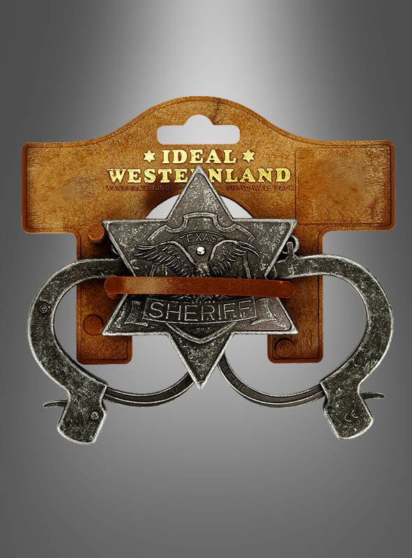 Das Sheriff-Set im Antik-Look, bestehend aus einer Spielzeug-Sheriff-Marke im Sheriffstern-Stil mit der Aufschrift „Texas Sheriff“ und daran befestigten Spielzeug-Handschellen der Marke „Ideal Western Land“, ist das perfekte Zubehör für ein Sheriff-Kostüm. Es wird auf einer braunen Verpackung vor grauem Hintergrund präsentiert und fängt so den Geist des Wilden Westens ein.