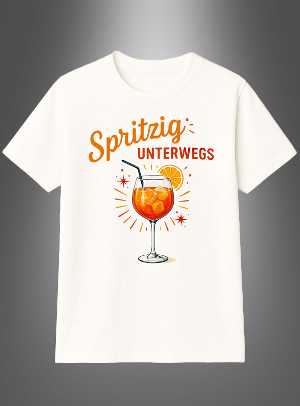 Das Cocktail-T-Shirt „Spritzig unterwegs“ ist ein weißes Shirt mit der Abbildung eines orangefarbenen Cocktails in einem Glas mit Strohhalm und Orangenscheibe, begleitet vom Schriftzug „Spritzig unterwegs“ oberhalb und neben dem Getränk. Es eignet sich perfekt als Sommer-Gruppenshirt oder Aperol-Spritz-T-Shirt für unterhaltsame Ausflüge mit Freunden.