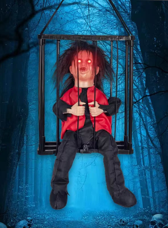 Eine animierte Halloween-Figur im Käfig mit leuchtend roten Augen und zerzaustem Haar schwebt vor dem Hintergrund eines dunklen, unheimlichen Waldes, in dem Totenköpfe auf dem Boden verstreut liegen – die perfekte Grusel-Deko für jede Spuk-Kulisse.