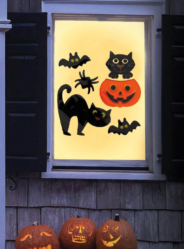 Ein Fenster, geschmückt mit dem Halloween-Fenster-Deko-Set aus Gel (20 x 19 cm), bestehend aus wiederverwendbaren Gel-Aufklebern mit Fledermäusen, schwarzen Katzen, einer Spinne, einer Jack-o'-Lantern und drei geschnitzten Kürbissen auf der Fensterbank. Die Szene erwacht jede Saison dank der wiederverwendbaren Fensteraufkleber zum Leben, die sich leicht anbringen lassen und Jahr für Jahr wiederverwendet werden können.