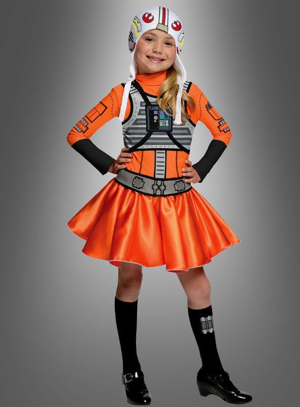 Ein Kind posiert in dem farbenfrohen „Star Wars X-Wing Fighter“-Kostüm für Mädchen, bestehend aus einem orangefarbenen Kleid im Piloten-Look und einem Helm, der von den X-Wing-Piloten aus „Star Wars“ inspiriert ist, vor einem grauen Hintergrund mit Farbverlauf. Dieses Karnevalskostüm fängt den Abenteuergeist eines echten X-Wing-Piloten perfekt ein.