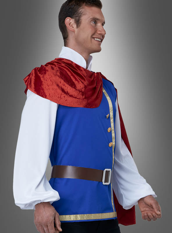 Ein Mann im „Klassischen Märchenprinz-Herrenkostüm“ – bestehend aus einer blauen Tunika mit goldenen Verzierungen, einem weißen Hemd, einem braunen Gürtel und einem roten Umhang – steht lächelnd vor einem grauen Hintergrund mit Farbverlauf; ideal für jede Märchen-Mottoparty oder als bezauberndes Märchenprinz-Karnevalskostüm.