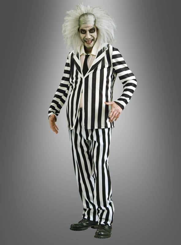 Eine Person, die das Original-Beetlejuice-Herrenkostüm trägt – bestehend aus einem schwarz-weiß gestreiften Anzug, wildem weißem Haar, blassem Make-up und schwarzen Schuhen –, steht vor einem grauen Hintergrund und verkörpert damit perfekt den kultigen Halloween-Look.