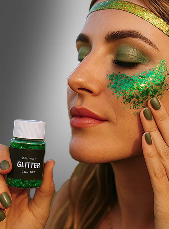 Eine Person trägt Glittergel-Make-up in verschiedenen Grüntönen auf ihre Wange auf und präsentiert so einen funkelnden Glitzer-Make-up-Look. Dazu trägt sie passenden grünen Lidschatten, grünen Nagellack und ein glänzendes grünes Stirnband.