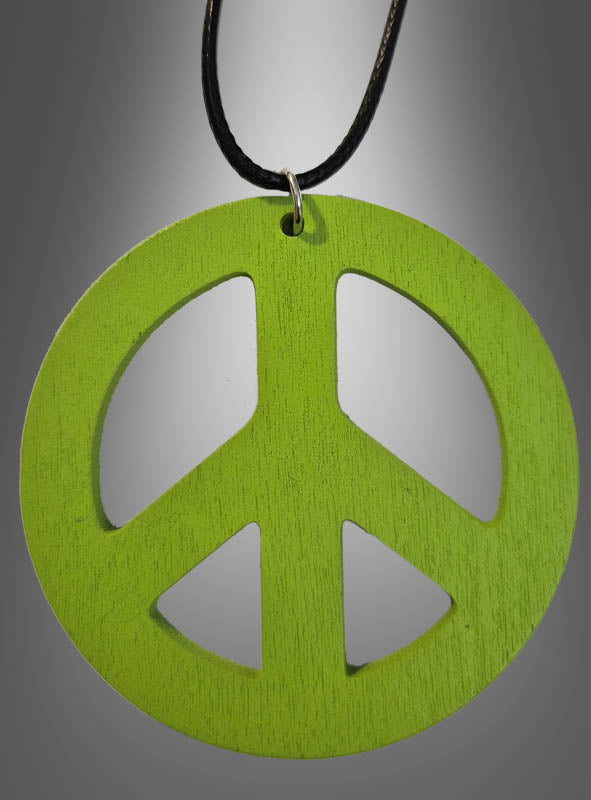 Eine 70er-Jahre-Friedenskette aus Holz (6,50 cm) mit einem grünen Holzanhänger in Form eines Peace-Zeichens hängt an einer schwarzen Kordel vor einem grauen Hintergrund mit Farbverlauf – perfekt als Peace-Zeichen-Kette oder Holzamulett für dein nächstes Hippie-Kostüm.