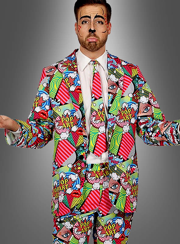 Ein Mann trägt den „Pop Art Anzug für Herren“ mit einem farbenfrohen Design im Comic-Stil, einer passenden Krawatte und einer von Comics inspirierten Gesichtsbemalung; er steht mit leicht ausgestreckten Armen und einem neutralen Gesichtsausdruck vor einem grauen Hintergrund.