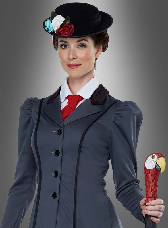 Eine Frau, die das „Nanny-Kostüm für Damen“ trägt – einen Anzug im Vintage-Stil und einen Hut mit floralen Akzenten, der an Mary Poppins erinnert –, posiert vor einem grauen Hintergrund und hält dabei einen roten Regenschirm mit einem papageienförmigen Griff in der Hand.