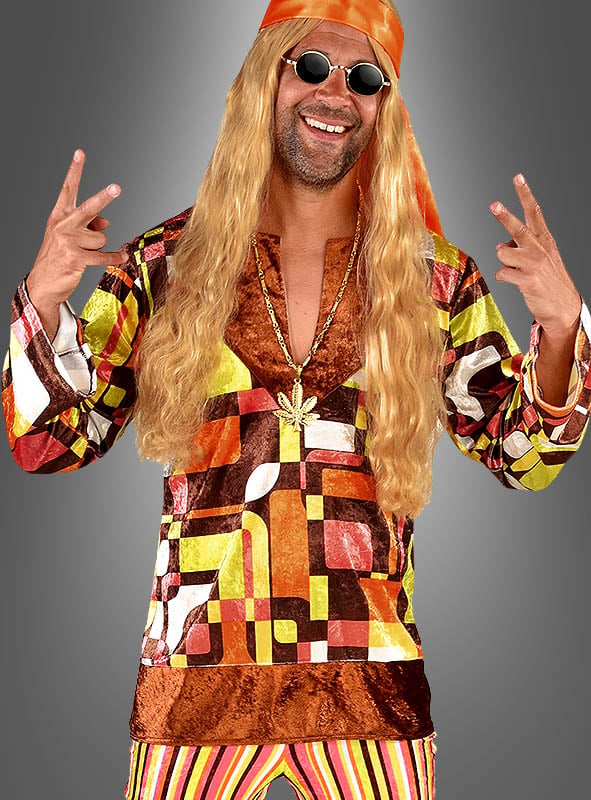 Mann im Karl Retro-Hippie-Herrenkostüm – komplett mit farbenfrohem Retro-Outfit, langer blonder Perücke, Stirnband, Sonnenbrille und einer Halskette mit Peace-Zeichen –, der lächelt und mit beiden Händen das Peace-Zeichen macht; perfekt für jede 70er-Jahre-Party oder als Hippie-Kostüm für Herren.