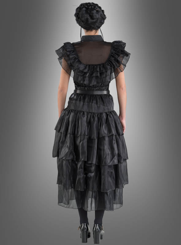 Eine Person steht mit dem Rücken zur Kamera und trägt das „Wednesday Damen Ballkleid“ – ein mehrlagiges schwarzes Rüschenkleid –, kombiniert mit schwarzen Leggings und schwarzen Stöckelschuhen, vor einem grauen Hintergrund mit Farbverlauf.