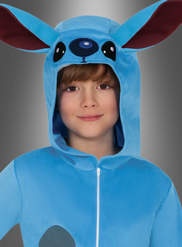 Ein Kind lächelt in die Kamera, während es den „Blauer Alien Overall“ trägt – ein blaues Kostüm mit großen Ohren und einer Kapuze, das wie ein Zeichentricktier gestaltet ist. Dieses bezaubernde Kinderkostüm ist perfekt für die Kleinen, die fantasievolles Spielen lieben.