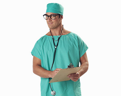 Eine Person in grüner OP-Kleidung, mit OP-Haube und Brille hält ein Klemmbrett in der Hand und trägt ein Stethoskop um den Hals; sie steht vor einem schlichten weißen Hintergrund.