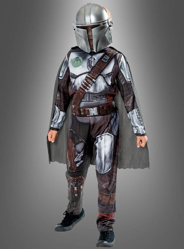 Ein Kind im Mandalorianer-Kinderkostüm aus „Star Wars“ – bestehend aus Helm, Umhang und bedruckter Rüstung – steht vor einem schlichten grauen Hintergrund – ideal für jeden jungen „Star Wars“-Kostümfan.