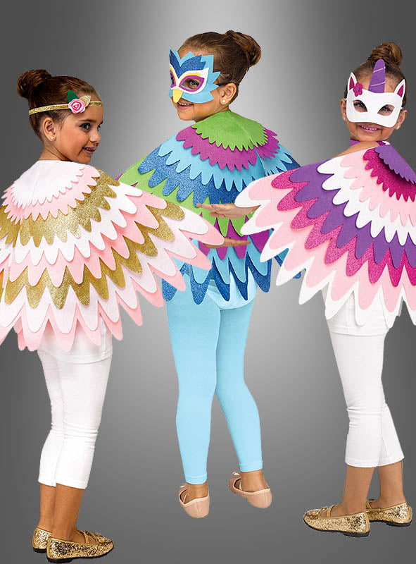 Drei Kinder in weißen und blauen Leggings tragen bunte, mit Federn verzierte Umhänge – darunter das schimmernde „Glitzer Cape Flügel für Kinder“ – sowie Tiermasken und posieren vor einem grauen Hintergrund.