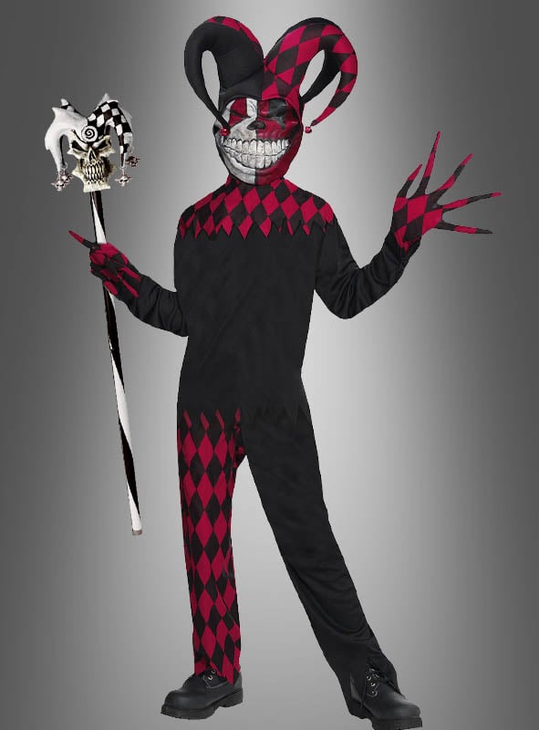 Vor einem grauen Hintergrund steht eine Person im „Jester Grusel Clown Kinderkostüm“ – ein schwarz-rotes Narrenkostüm mit einer großen Maske, die ein unheimliches Grinsen zeigt –, die einen Narrenstab in der Hand hält und Handschuhe mit langen, spitzen Fingern trägt.