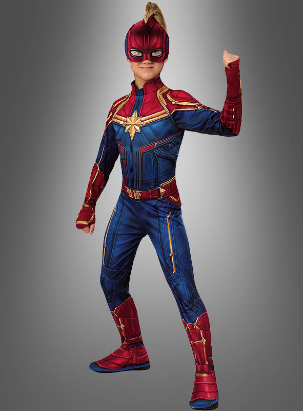 Ein Kind in einem „Captain Marvel für Mädchen“-Kostüm posiert mit erhobener Faust. Es trägt einen rot-blau-goldenen Anzug, komplett mit Maske und Stiefeln, vor einem grauen Hintergrund – das ideale Marvel-Superheldinnen-Kostüm für jede Karnevalsfeier.
