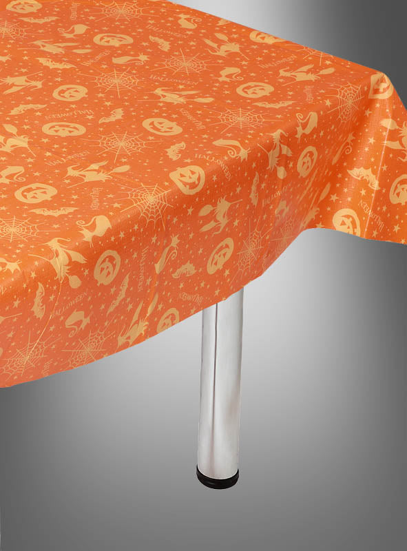 Mehrweg-Tischdecke zu Halloween mit festlichen Motiven wie Kürbissen, Spinnen, Fledermäusen und Sternen – ideal als stimmungsvolle Halloween-Dekoration oder Kürbis-Tischdecke, stilvoll drapiert über einem rechteckigen Tisch mit sichtbaren Metallbeinen.