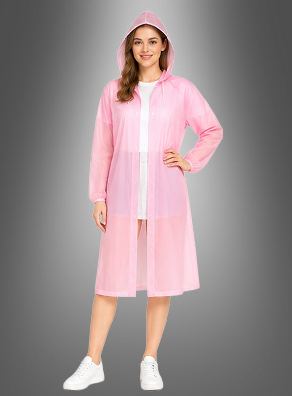 Eine Frau, die den „Langer Regenmantel wetterfest“ in Rosa über einem weißen Outfit und weißen Sneakers trägt und vor einem grauen Hintergrund mit Farbverlauf steht.