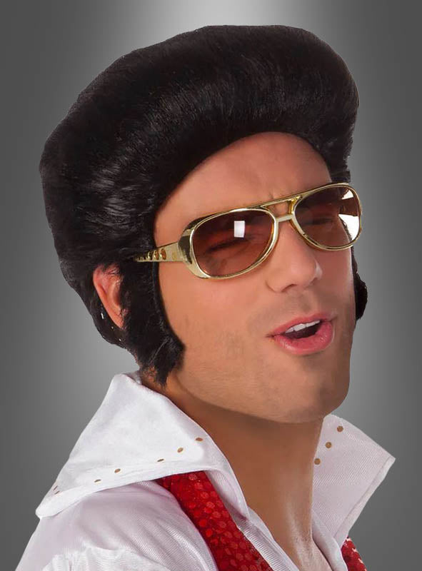 Eine Person mit schwarzer Perücke, einer „Elvis Brille Original Lizenz gold“, einem weißen Hemd mit Kragen und einem roten Schal posiert mit leicht geöffnetem Mund vor einem grauen Hintergrund – perfekt für jede 70er-Jahre-Kostümparty.
