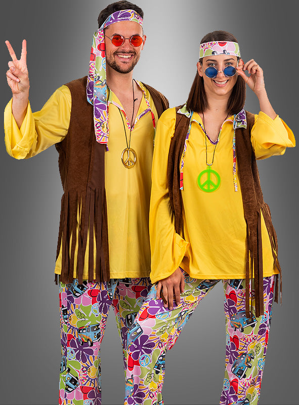Zwei Personen in farbenfrohen Hippie-Kostümen aus den 1970er Jahren – komplett mit Peace-Zeichen-Halsketten, Westen, Stirnbändern und runden Sonnenbrillen – stehen lächelnd vor einem grauen Hintergrund. Ihr lebhaftes 70er-Jahre-Hippie-Bernd-Herrenkostüm fängt den Geist von „Flower Power“ und den verspielten Stil eines jeden Herrenoutfits aus den 70er Jahren perfekt ein.