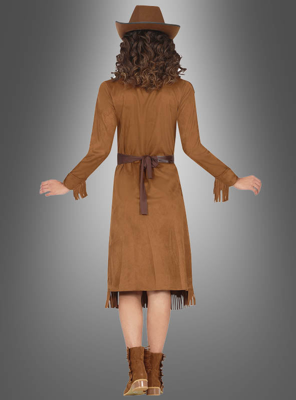 Eine Frau präsentiert das „Cowgirl Western Kleid Damen“ mit braunen Fransen, einem passenden Hut und Stiefeln. Sie steht mit leicht angehobenen Armen und dem Rücken zur Kamera vor einem grauen Hintergrund mit Farbverlauf.