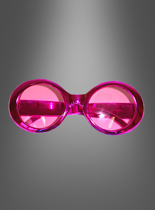 Hippie-Brille im Metallic-Look: Eine pinkfarbene, runde ausgefallene Brille mit Kunststoffrahmen und getönten Gläsern fängt den verspielten Charakter einer Retro-Brille aus den 70er Jahren ein und wird vor einem grau verlaufenden Hintergrund präsentiert.