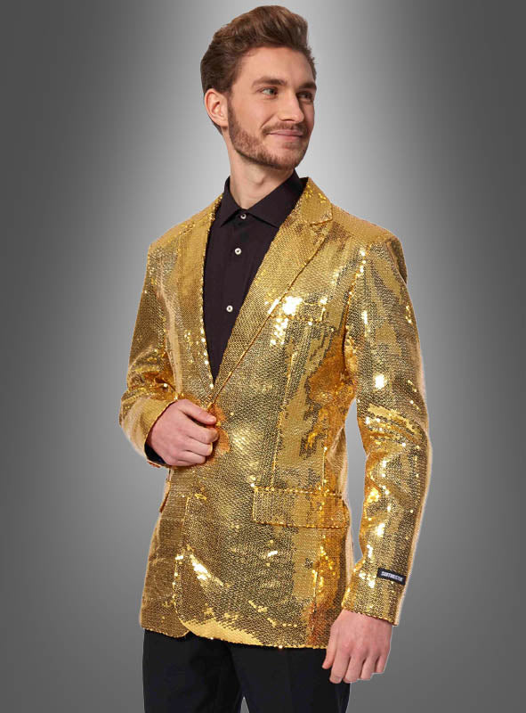 Ein Mann, der die „Pailletten Jackett Herren Gold“ über einem schwarzen Hemd trägt, steht vor einem schlichten grauen Hintergrund mit Farbverlauf, blickt leicht zur Seite und lächelt.