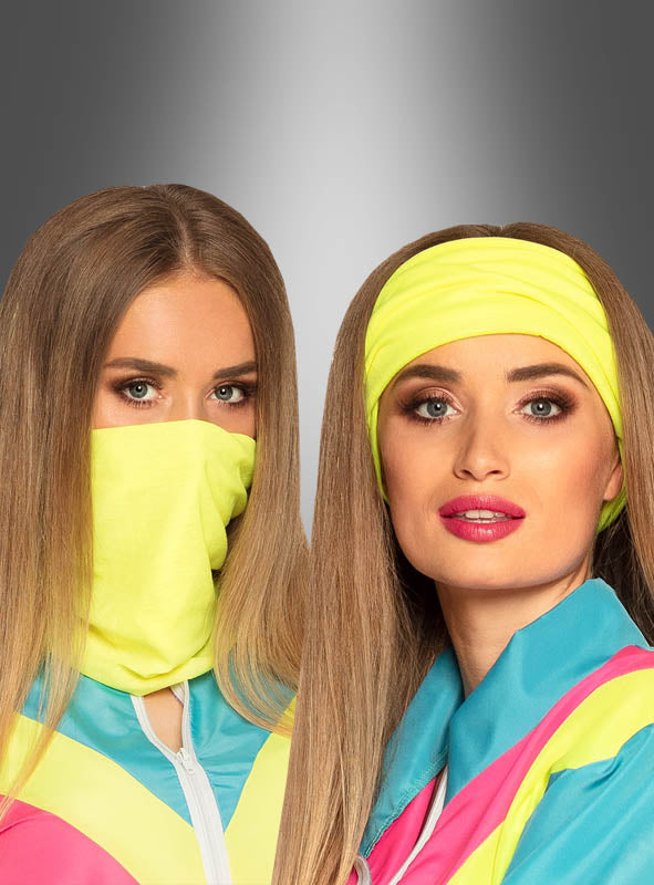 Zwei Frauen mit langen Haaren tragen farbenfrohe Jacken, die vom Neon-Trainingsanzug der 80er Jahre inspiriert sind; die eine trägt ein gelbes Stirnband und rosa Lippenstift, während die andere ihr Gesicht teilweise mit einem gelben Tuch verdeckt. Ihre auffälligen Outfits verkörpern den ikonischen Retro-Stil, während sie vor einem grauen Hintergrund mit Farbverlauf posieren.