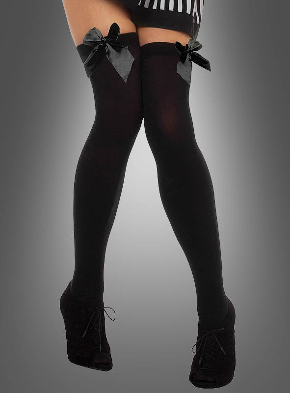 Eine Person trägt schwarze Schuhe mit hohen Absätzen, sexy Overknee-Stiefel mit Schleife in Form von schwarzen, bis zum Oberschenkel reichenden Strümpfen, die mit großen Schleifen verziert sind, sowie einen schwarz-weiß gestreiften Rock vor einem einfarbigen Hintergrund mit Farbverlauf.
